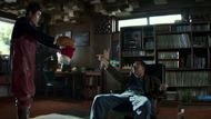 Man-soo points at a man sitting on a couch. (Image via CJ Entertainment)